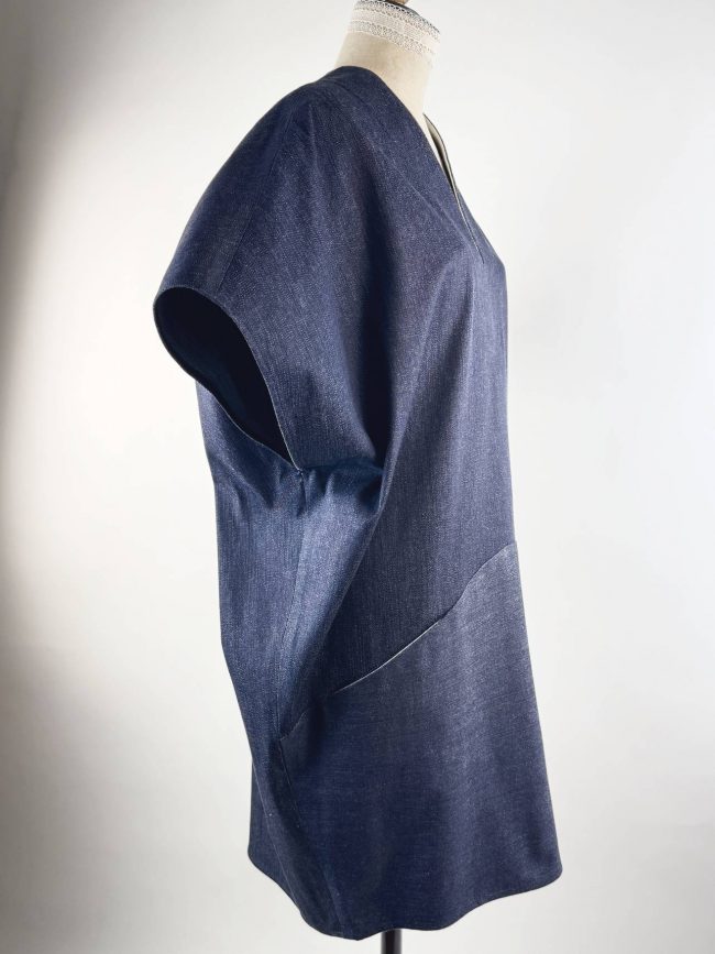 Robe ample sans manches en jean bleu marine, col en V, coupe trapèze fluide et contemporaine. vue coté