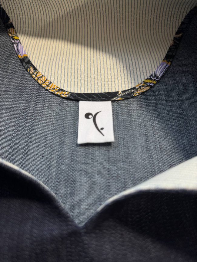 Robe ample sans manches en jean bleu marine, col en V, coupe trapèze fluide et contemporaine. Détail encolure