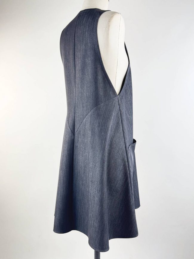 Robe trapèze sans manches en tissu effet jean noir, col en V, avec deux grandes poches plaquées. Cotés 3/4