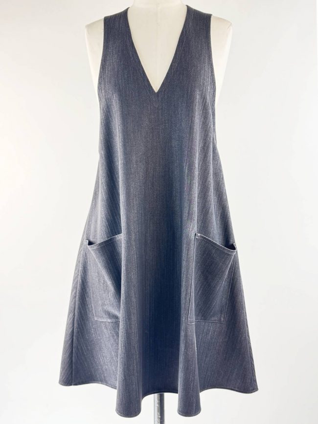 Robe trapèze sans manches en tissu effet jean noir, col en V, avec deux grandes poches plaquées. Face