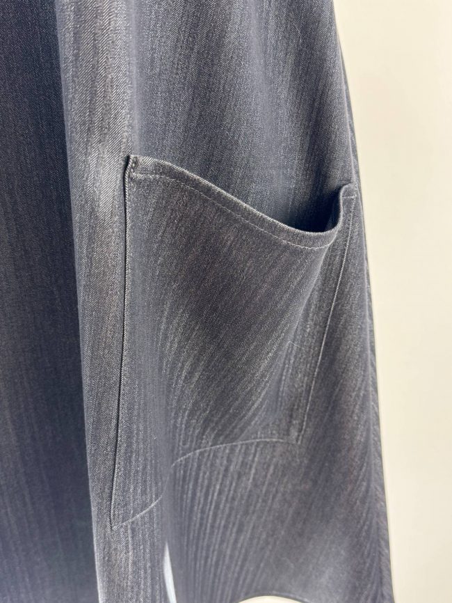Robe trapèze sans manches en tissu effet jean noir, col en V, avec deux grandes poches plaquées. Détail poche